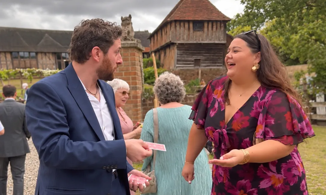 Guy Samuels performing a card trick for a laughing guest at a wedding